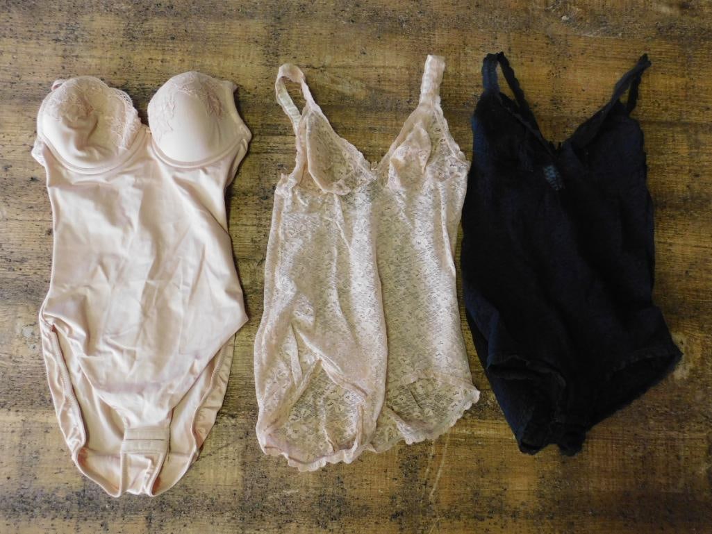 Set of Three Women?s Lingerie Items With Lace Designs: This set includes three pieces of women's lingerie. The first item is a light beige bodysuit featuring lace details and padded cups. The second is a sheer lace camisole in a creamy beige tone. The
