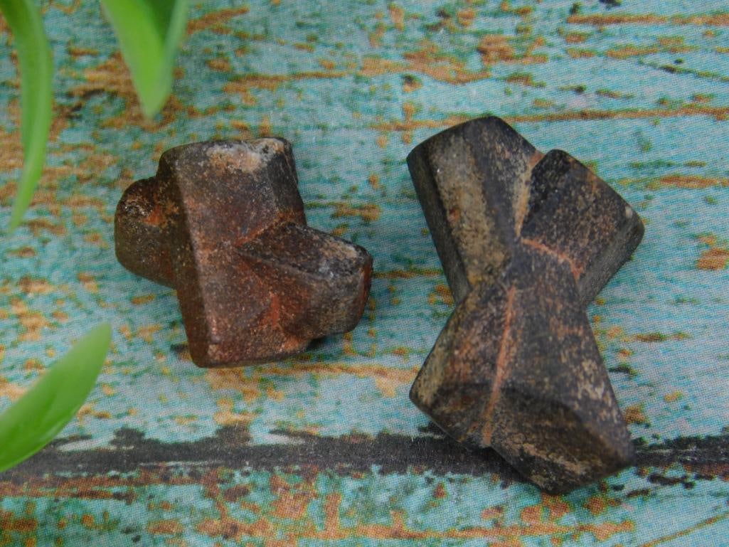Pair of Fairy Cross Stones for Collection: This lot includes two naturally occurring fairy cross stones. Each piece displays the characteristic twinned crystal formation. A coin is shown for size reference, but exact dimensions are not specifi