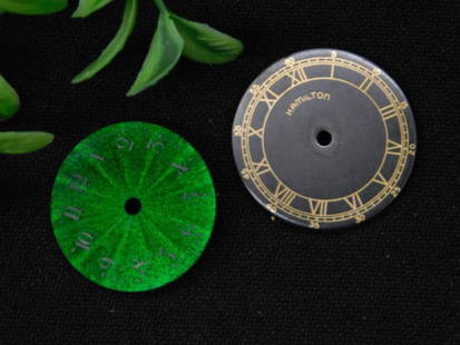 Two Vintage Watch Faces, Hamilton and Green Sunburst WATCHMAKER WATCHMAKING TOOLS: - Includes two vintage watch faces: one Hamilton dial with black and gold design, and one green sunburst-styled dial. | - Hamilton dial features Roman numeral design and brand name at the center. | -