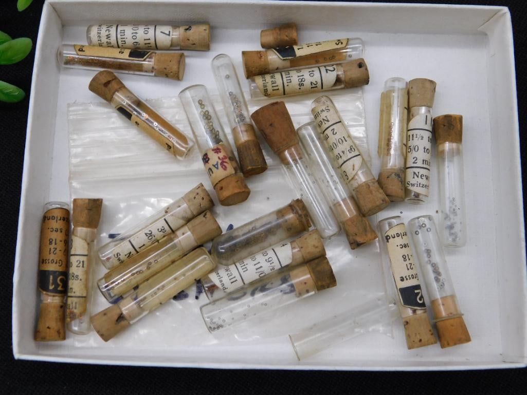 Vintage Glass Vials with Cork Stoppers and Timing Washers WATCHMAKER WATCHMAKING TOOLS: - Collection of vintage glass vials with cork stoppers, assorted sizes. | - Labels on vials indicate various markings, numbers, and some handwritten notes. | - Includes contents referred to as 'timing