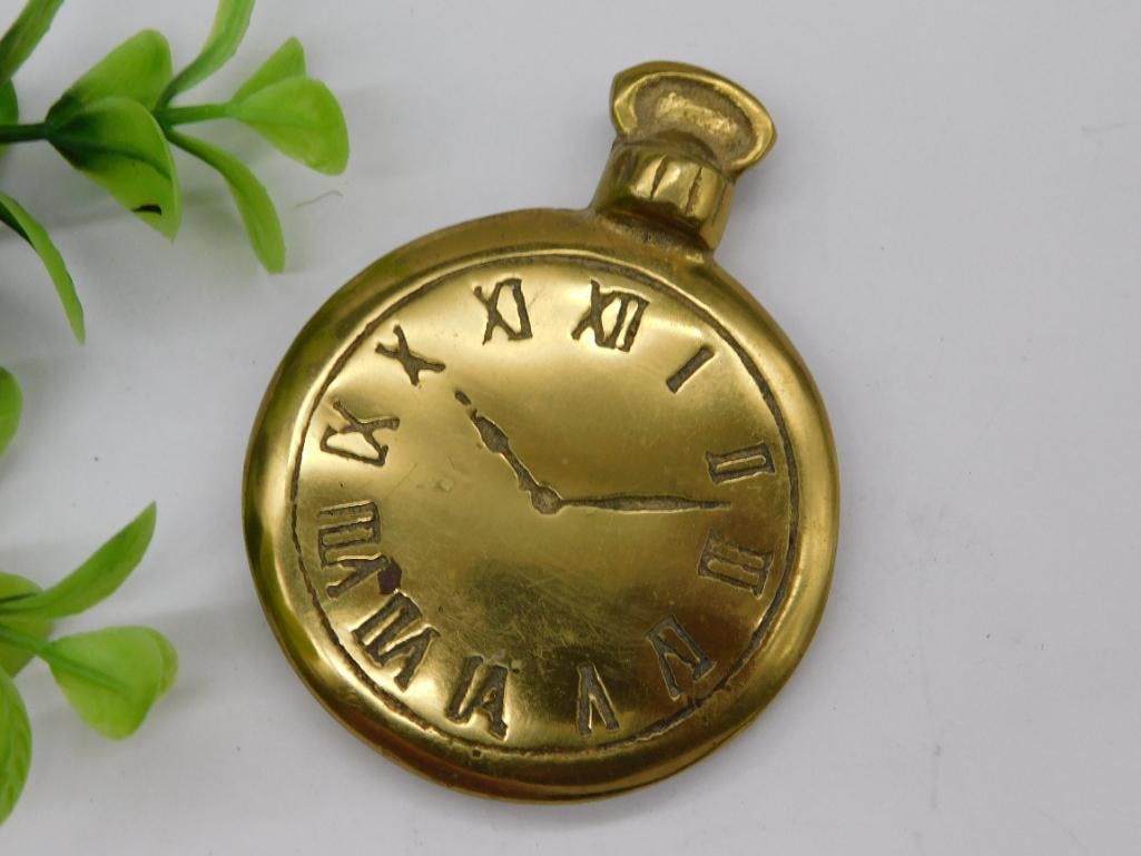 Round Brass Pocket Watch Replica Paperweight: - Decorative brass pocket watch-shaped design. | - Features Roman numeral markings on the front. | - Non-functional item, suitable for use as a paperweight or decor. | - Made entirely of brass with a 