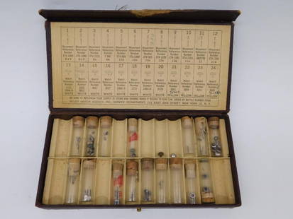 Vintage Wyler Watch Parts Box with Components WATCHMAKER WATCHMAKING TOOL: - Vintage Wyler watch parts set housed in a worn leather case. | - Contains multiple vials with small watch components such as stems and crowns. | - Includes a detailed reference chart printed on the