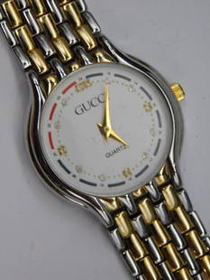 Gucci Quartz Watch with Two-Tone Metal Band WATCHMAKER WATCHMAKING TOOL: - Designer wristwatch by Gucci with a quartz movement. | - Two-tone metal band featuring silver and gold tones in a woven pattern. | - White dial with gold-tone hands, logo details, and numeral-free