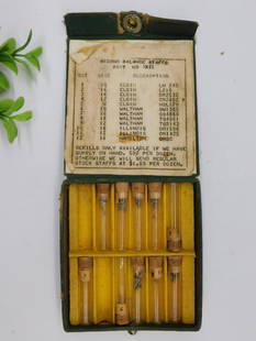 Vintage Boxed Set of Watchmakers Pivot Staffs WATCHMAKER WATCHMAKING TOOLS: Vintage green fabric-covered box containing watchmaker's pivot staffs. | Includes multiple glass vials with cork stoppers, each labeled with corresponding numbers. | Vials contain fine pivot staffs de
