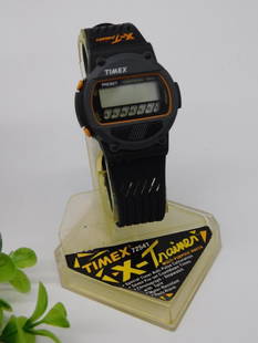 Timex Mens Digital Sports Watch with Original Box WATCHMAKER WATCHMAKING TOOLS: Timex digital sports watch designed for men. | Features a black strap and gray face with orange accents. | Includes original box and stand for storage or display. | Functions include stopwatch and sta