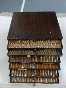Vintage Watchmakers Cabinet with Labeled Parts Drawers WATCHMAKING WATCHMAKER TOOLS: Vintage wooden watchmaker's cabinet with multiple drawers. | - Each drawer contains labeled compartments with glass vials. | - Vials are cork-topped and contain various small watch parts, including fr
