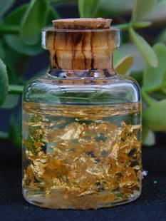 Miniature Bottle With Real 22K Gold Flakes ROCK STONE LAPIDARY SPECIMEN: - Miniature glass bottle containing real 22-karat gold flakes. | - Sealed with a cork stopper for secure display and storage. | - Accompanied by a label indicating the contents as 'Real 22K Gold Flake
