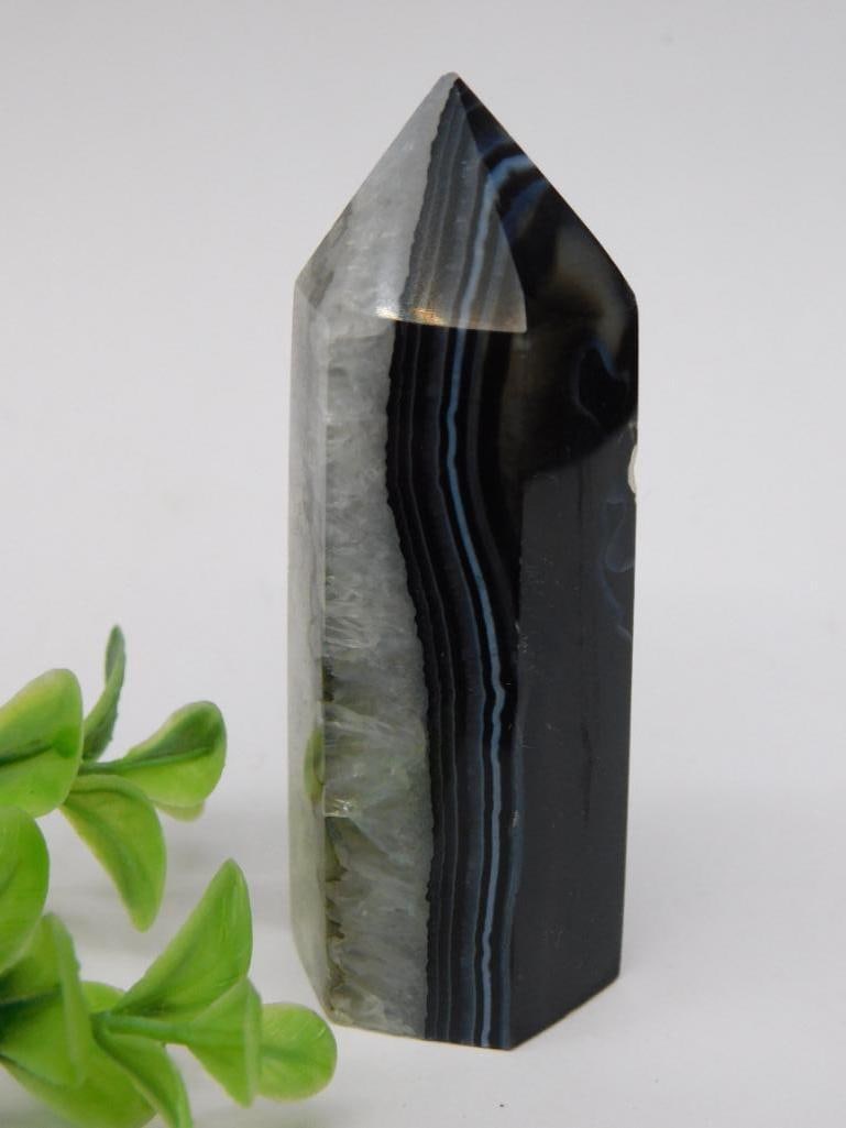 Black Banded Agate Tower Rock Stone Lapidary Specimen: - Polished Black Banded Agate crystal point with striped patterns. | - Features smooth edges and a pointed tip for display or collection purposes. | - Compact size and dimensions indicated by adjacent