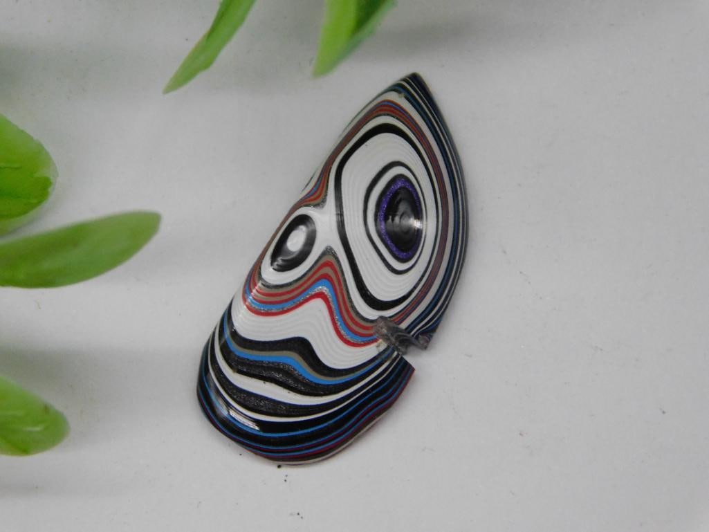 Colorful Fordite Motor City Agate Slice with Abstract Pattern: - A colorful slice of Fordite featuring layered patterns and an abstract design. | - Origins of this material trace back to layered car paint overspray, giving it vibrant and unique textures. | - Appr