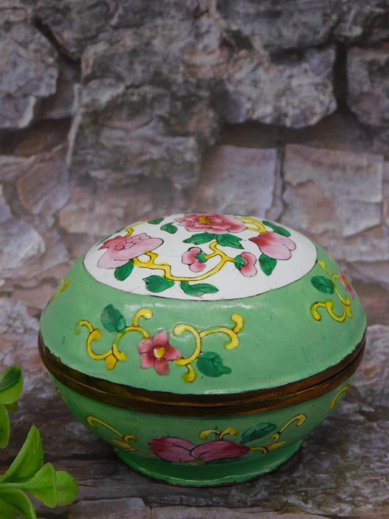Green Cloisonne-Style Round Hinged Box: Round, hinged decorative box with vibrant green exterior showcasing floral designs in pink, white, and yellow. Interior finished in a lighter green shade. Features a brass or gold-tone rim for added s