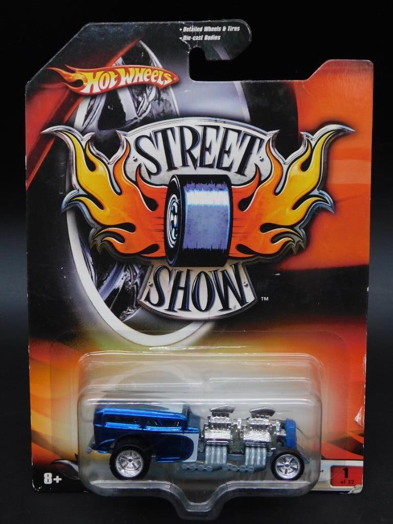 Hot Wheels Street Show Car in Packaging: Hot Wheels Street Show die-cast car in its original packaging. The packaging features strong branding and an eye-catching design. The car appears untouched and remains in its factory-sealed plastic ca