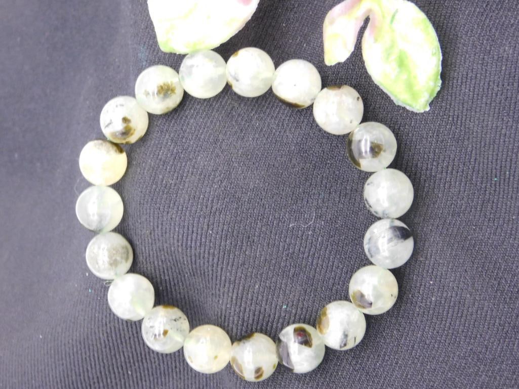 Green Gemstone Beaded Stretch Bracelet ROCK STONE LAPIDARY SPECIMEN: A stretchable bracelet featuring round green gemstone beads. Each bead showcases unique patterns, with subtle variations in color and texture. The bracelet's size appears suitable for a variety of