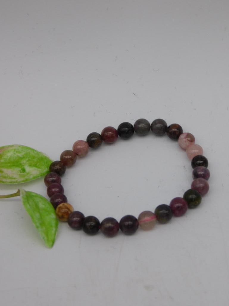 Multicolor Stone Beaded Stretch Bracelet ROCK STONE LAPIDARY SPECIMEN: This bracelet features multicolored round beads arranged on a stretchable cord. The beads showcase shades of pink, purple, and dark tones, providing a variety of natural hues. Comes as part of Lot 708