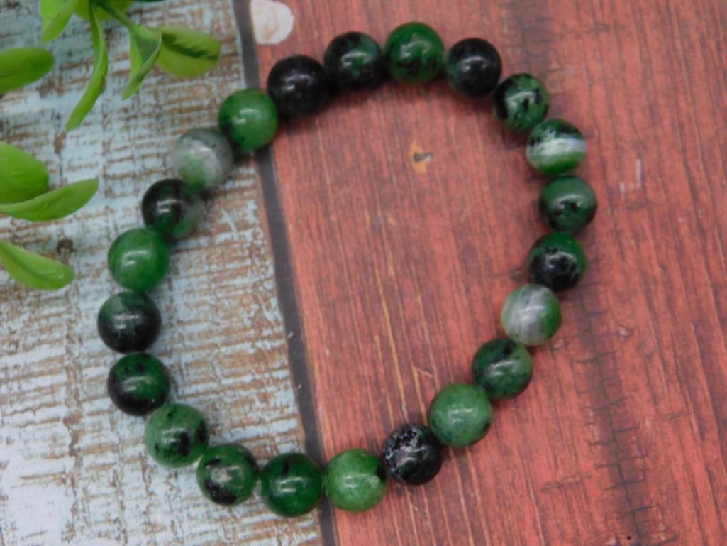 Green and Black Beaded Bracelet With Elastic Band: This bracelet features round green and black beads strung on an elastic band, allowing for adjustable wear. The beads vary in shades, adding a distinctive appearance. The lot includes a total of one b