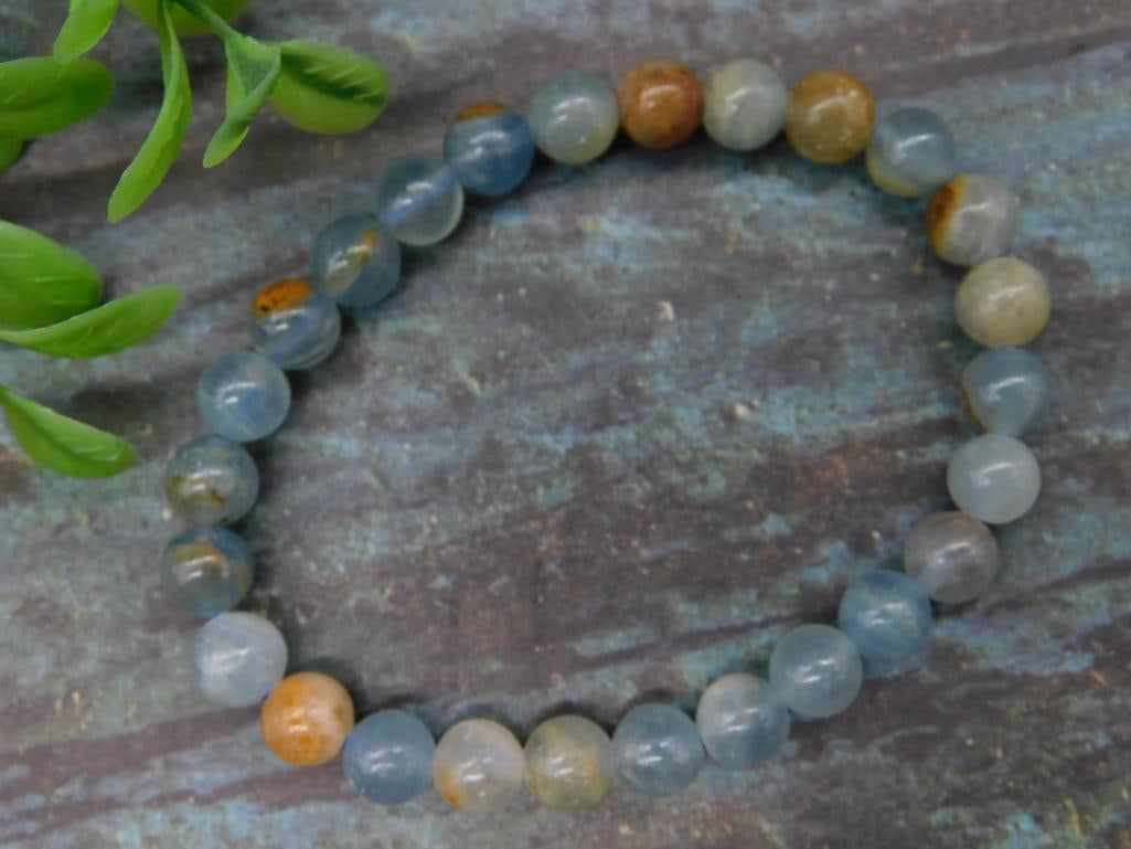 Beaded Gemstone Bracelet with Mixed Tones: This beaded gemstone bracelet features round beads in a blend of blue and earthy tones. Each bead showcases natural variations in color and inclusions, creating a unique look. The bracelet is elastic,