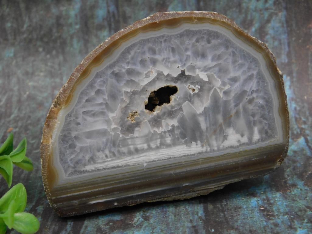 Agate Rock Stone Lapidary Specimen: Polished geode half showcasing a crystalline interior surrounded by layered banding. Back of the geode displays a natural, unpolished surface. Approximate weight is 414 grams. The quarter in the image
