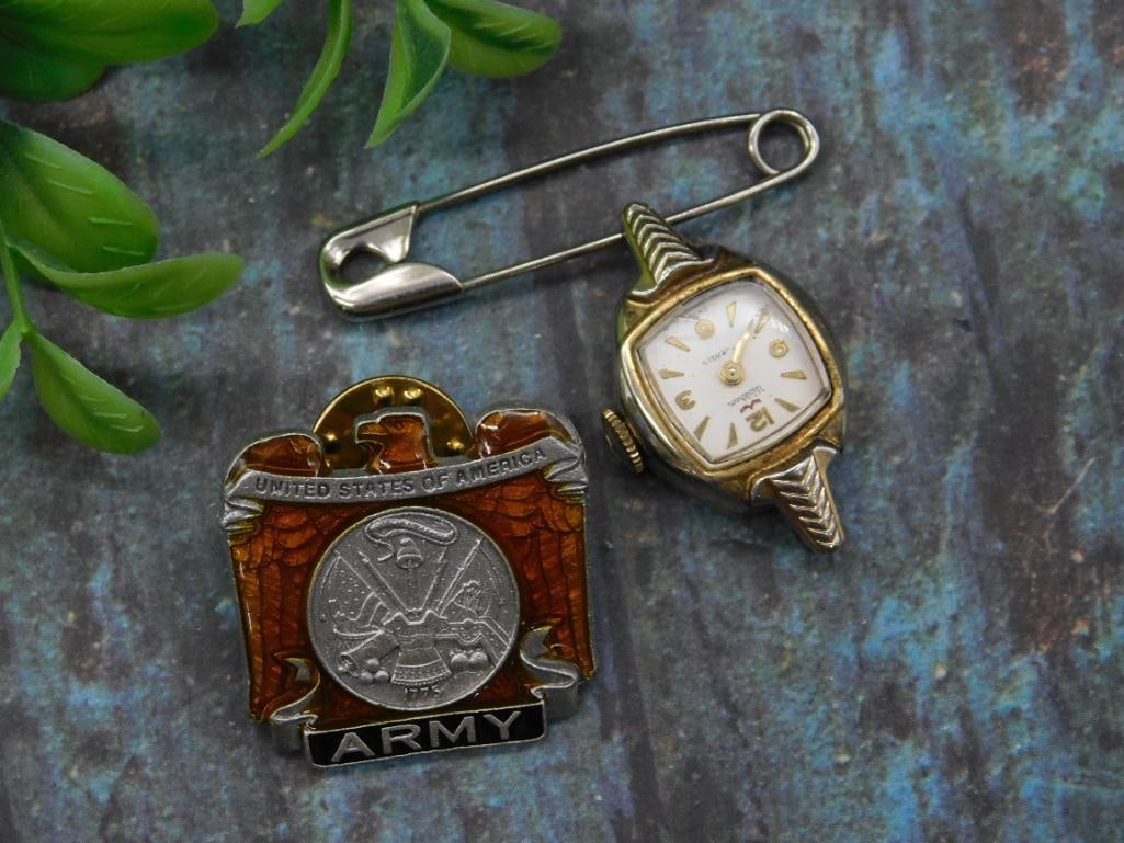 Set of US Army Lapel Pin and Ladies Wristwatch: This lot features a US Army lapel pin with red and silver tones, marked 'Made in USA,' alongside a ladies wristwatch with gold-tone casing and white dial. The wristwatch is attached to a safet