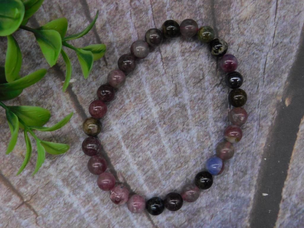 Multi-Color Beaded Stone Bracelet: A bracelet featuring an assortment of multi-color stone beads. Each bead is uniformly round, strung together with an elastic cord for easy wear. Includes a range of polished tones and patterns. The qu