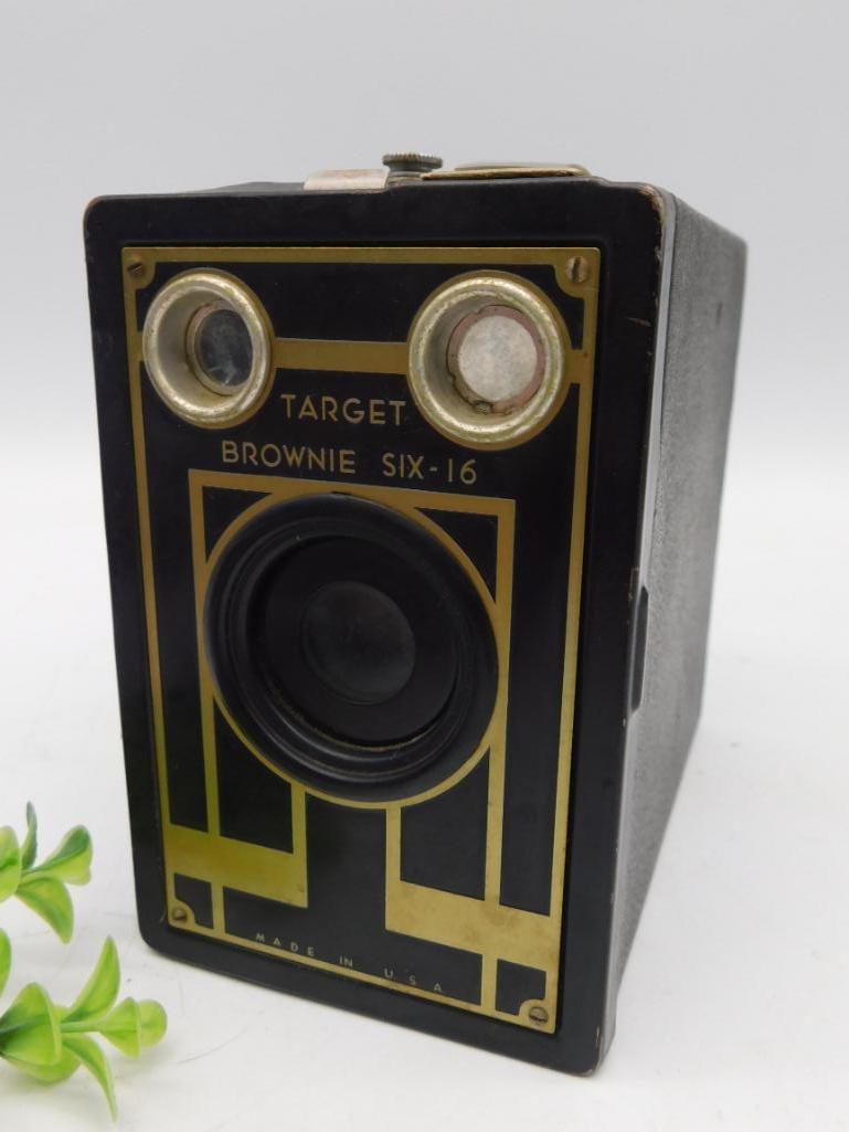 Kodak Target Brownie Six-16 Box Camera: Kodak Target Brownie Six-16 box camera featuring a black body with gold-tone accents. Includes two lens openings on the front and a simple viewfinder on the top. The camera shows signs of wear consist