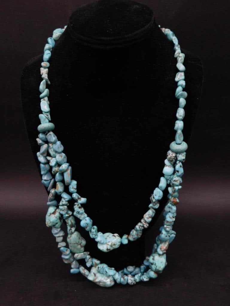 Three-Strand Turquoise Nugget Beaded Necklace Displayed: - Three-strand necklace featuring turquoise nugget beads in varying shapes and sizes. | - Appears to be hand-strung, showcasing a unique, natural aesthetic. | - Turquoise stones display natural matrix