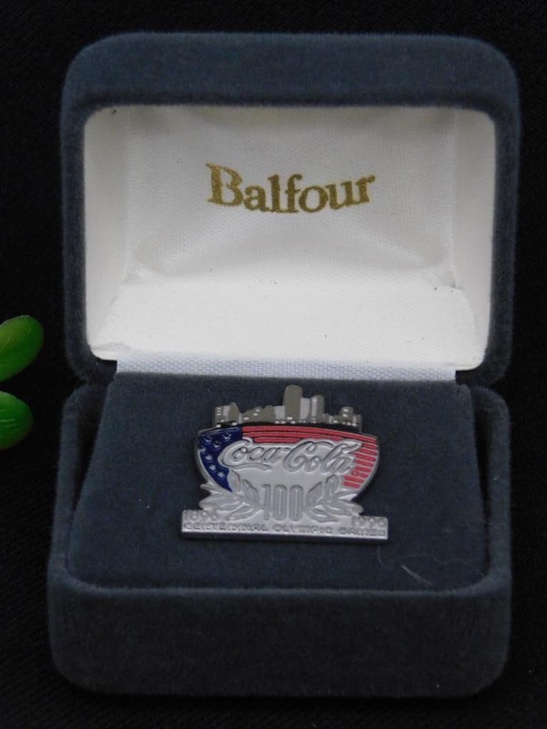 Coca-Cola Skyline Pin in Velvet Box: - Limited edition Coca-Cola Skyline Pin, numbered 873 out of 2500. | - Crafted by Balfour, housed in the original velvet presentation box with branding. | - Features a patriotic design with the Coca-C