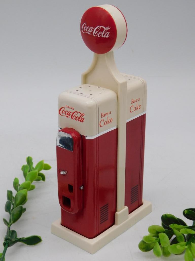 Vintage Coca-Cola Gas Pump Salt and Pepper Shakers: - Vintage salt and pepper shakers designed as Coca-Cola gas pumps. | - Made of plastic material with red and white Coca-Cola branding. | - Features a nostalgic gas pump design with raised Coca-Cola lo