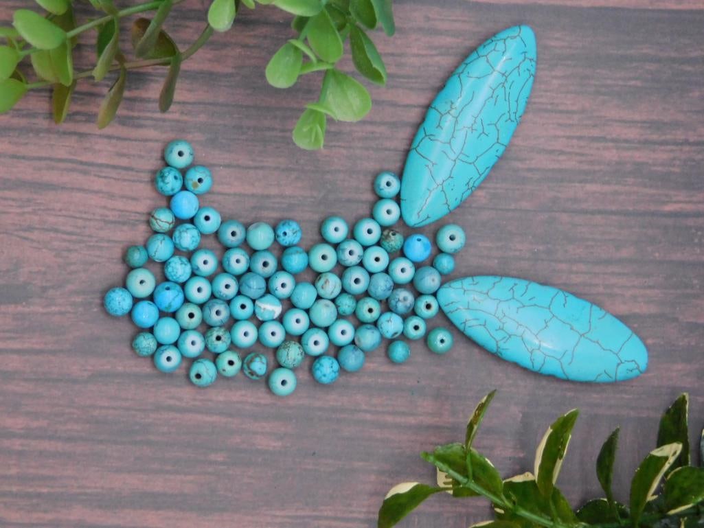Turquoise Beads and Oval Cabochons: - Includes a mixture of turquoise beads in various sizes and shapes. | - Features two elongated oval turquoise cabochons with a distinct veining pattern. | - Beads and cabochons exhibit a characterist