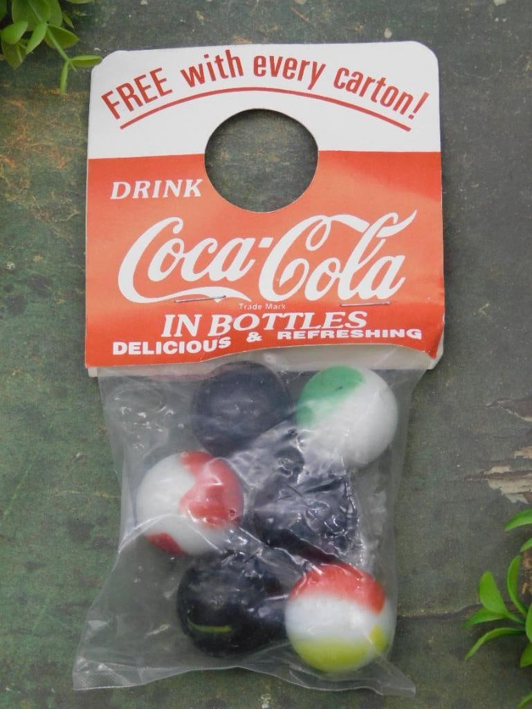 Vintage Coca-Cola Bottle Cap Shooter Marbles in Bag: - Includes a set of shooter marbles sealed in original plastic bag. | - Comes with attached vintage Coca-Cola promotional card featuring the text 'Free with every carton.' | - Marbles are multi-colore