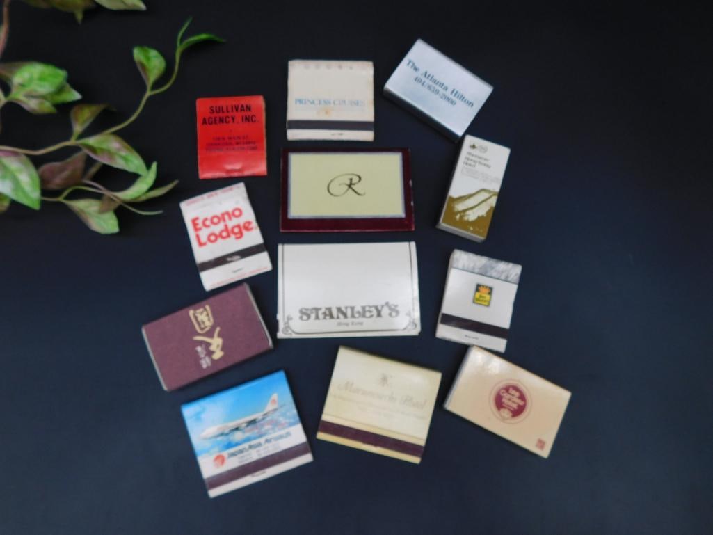 Collection of 12 Matchbooks and Matchboxes: This lot features 12 matchbooks and matchboxes from various establishments, including hotels, airlines, and businesses. Each item displays unique logos and designs. Condition varies, with some matchbo