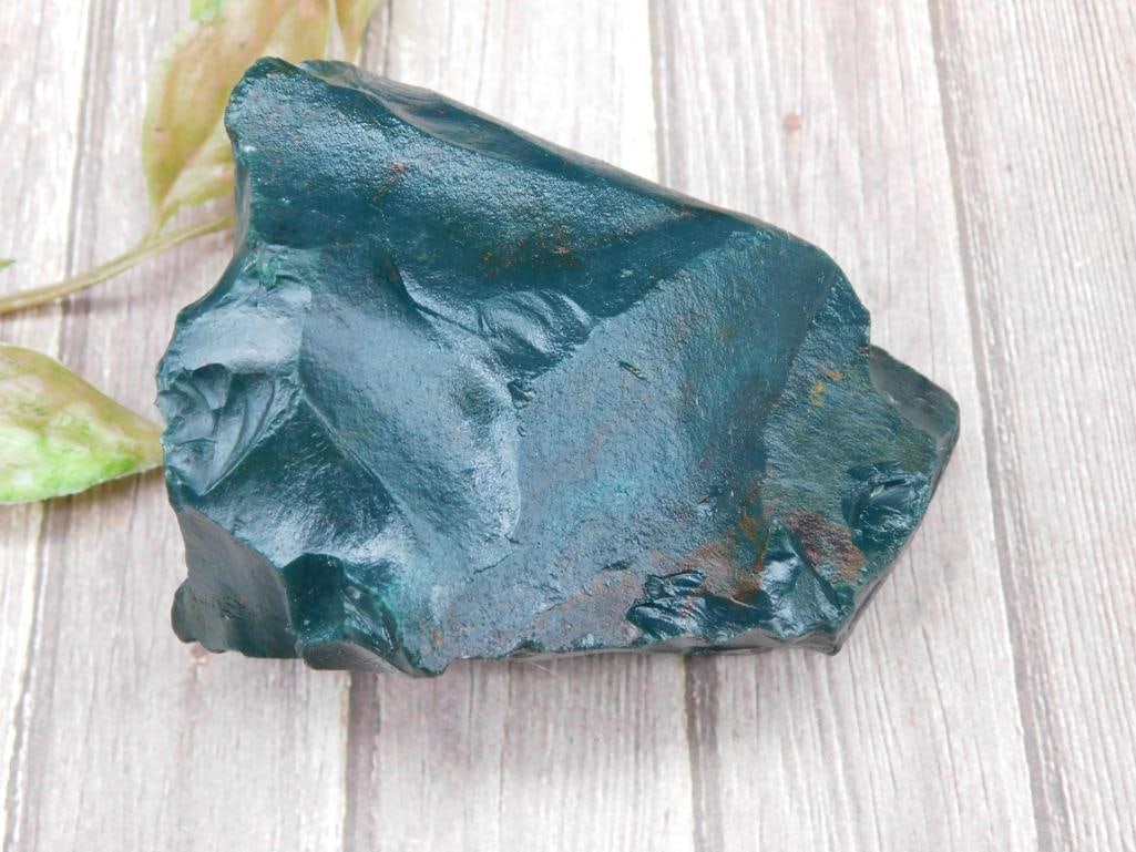 Bloodstone Rock Stone Lapidary Specimen, 204 Grams: This lot features a rough green obsidian stone weighing 204 grams. The natural green hues are visible throughout the piece. It features raw, jagged edges and a glossy finish on certain areas from natu