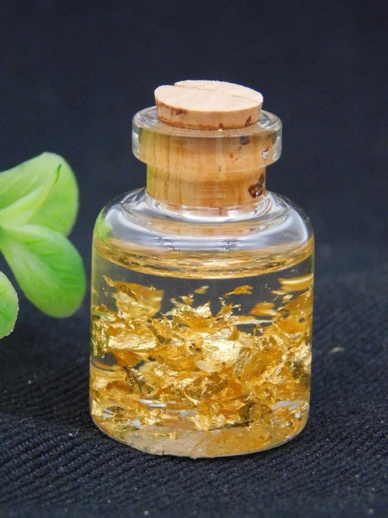 Miniature Jar with Real 22K Gold Flakes Rock Stone Lapidary Specimen: Contains visible flakes of 22K gold suspended in liquid. | Miniature glass jar sealed with a cork stopper. | Weighs approximately 13 grams as indicated on the auction label. | Includes original labeli