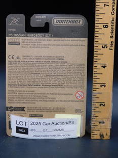 1995 Nissan Hardbody (D21) Matchbox Car Package: Factory-sealed package of a Matchbox 1995 Nissan Hardbody (D21) model car. The packaging includes detailed product information and safety instructions. A label indicating Lot 2025 from a car auction/e