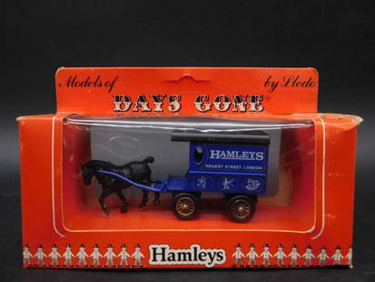 Hamleys Days Gone Die-Cast Horse and Cart Model: This lot features a Hamleys 'Days Gone' die-cast metal model of a horse and cart by Lledo. The model is displayed in its original packaging, boasting vibrant Hamleys branding on the cart. The box exhi