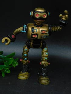 Gold Robot Action Figure from Fisher-Price, 1990: - Vintage robot action figure manufactured by Fisher-Price in 1990. | - Crafted in gold-tone plastic with various painted details in red, blue, and black. | - Features fully articulated arms and legs