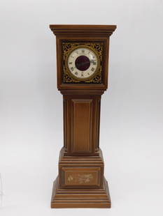 Vintage WITTNAUER FRENCH Wooden Mantel Clock with Roman Numerals: - Wooden mantel clock featuring a rectangular design with decorative carvings. | - Clock face adorned with Roman numerals and ornate brass-like detailing. | - Includes a keyhole on the back for windin
