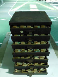 Vintage Multi-Drawer Watch Component Cabinet WATCHMAKING WATCHMAKER TOOLS: - Multi-drawer metal storage cabinet, contains labeled compartments. | - Filled with inventory of watch components, notably Bulova and Elgin labeled packets. | - Includes envelopes marked with specifi
