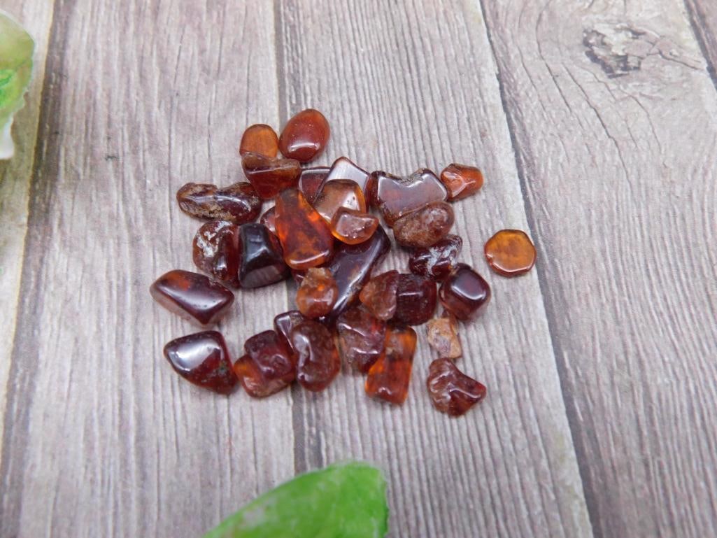 Collection of 12 Grams of Orange Garnet Gemstones: A lot consisting of 12 grams of small, polished amber stones. Each piece shows natural variations in color, with warm reddish-brown and golden hues. Suitable for collectors or potential crafting purpo