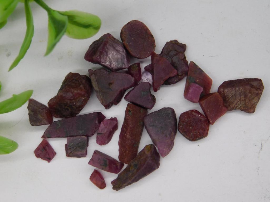 Collection of Uncut Red Gemstones Rock Stone Lapidary Specimen: A collection of uncut red gemstones, varying in shape and size. The stones exhibit natural rough surfaces with some angular and irregular shapes. Total weight is noted as 12 grams. A U.S. quarter is s