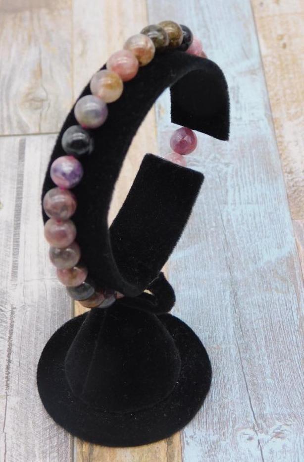 Multi-Color Stone Beaded Stretch Bracelet: This bracelet features polished multi-color stone beads strung on a stretchable cord for adjustable wear. The stones vary in shades of pink, red, and earth tones, creating a vibrant visual appeal. Ide