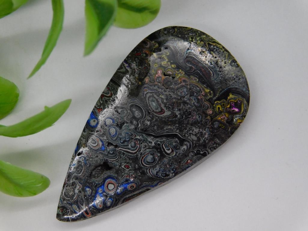 Fordite Motor City Agate Cabochon Rock Stone Lapidary Specimen: Polished teardrop-shaped Fordite cabochon. Features a multicolor pattern with swirls and layers formed by the accumulation of enamel paint from automotive factories. Measures approximately 3 grams in