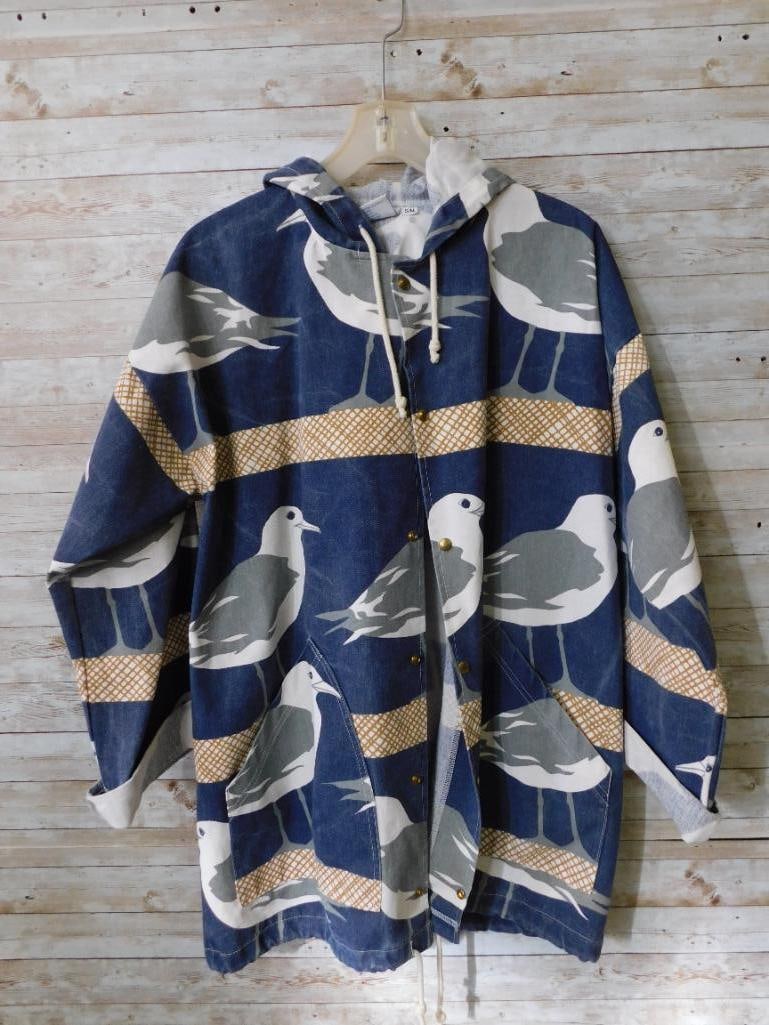Michigan Rag Co S/M Jacket With Seagull Print: Michigan Rag Co lightweight jacket in size S/M. Features a seagull-themed print on a blue background with yellow accent patterns. Drawstring hood for adjustable fit. Comfortable fabric with visible st