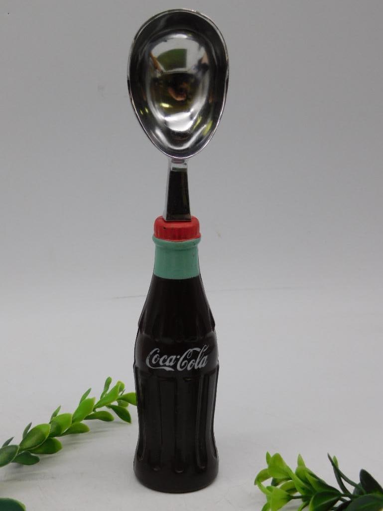Vintage Coca-Cola Bottle Spoon Utensil: - Decorative spoon with a handle designed as a Coca-Cola glass bottle replica. | - Features the Coca-Cola logo in white on the bottle's side. | - Metal spoon is securely attached to the bottle-shaped
