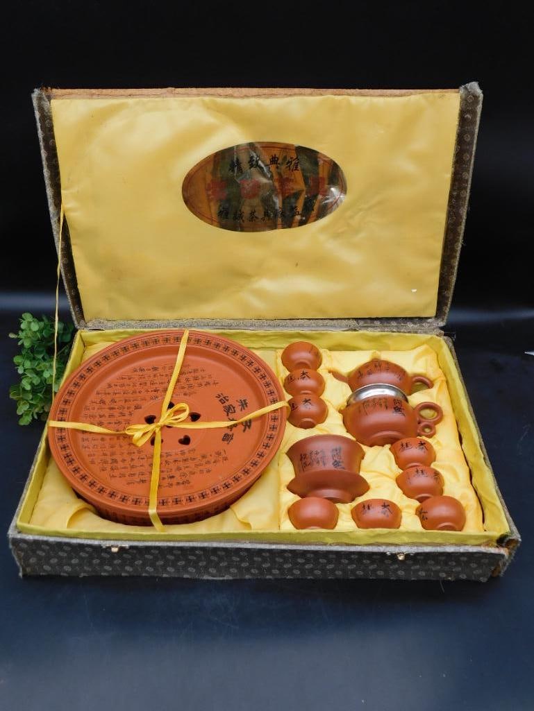 Chinese Yixing Zisha Clay Tea Set with Gift Box: Complete tea set crafted from Yixing Zisha clay. | Includes a teapot, tea cups, a gaiwan, and a serving pitcher. | Accompanied by a matching round tea tray with inscriptions. | Housed in a decorative