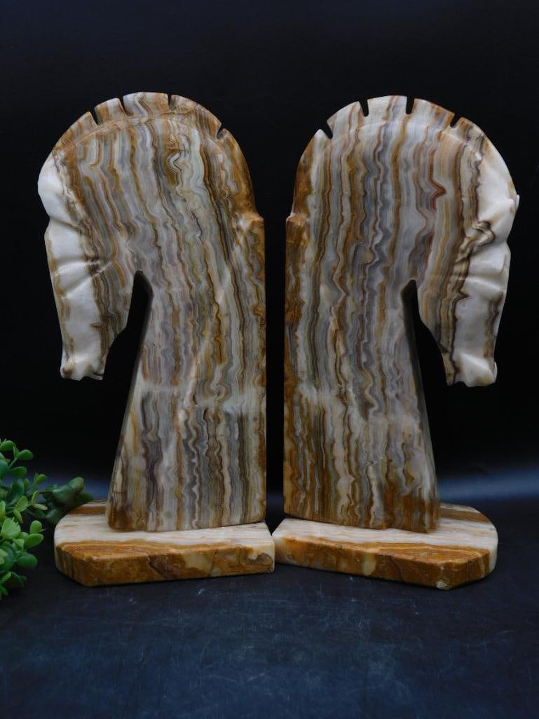 Onyx Horse Head Bookends in Earth Tones: Crafted from natural onyx with detailed horse head silhouettes. | Features layered earth tones, including shades of brown, cream, and beige. | Mounted on flat bases for stability, suitable for functio
