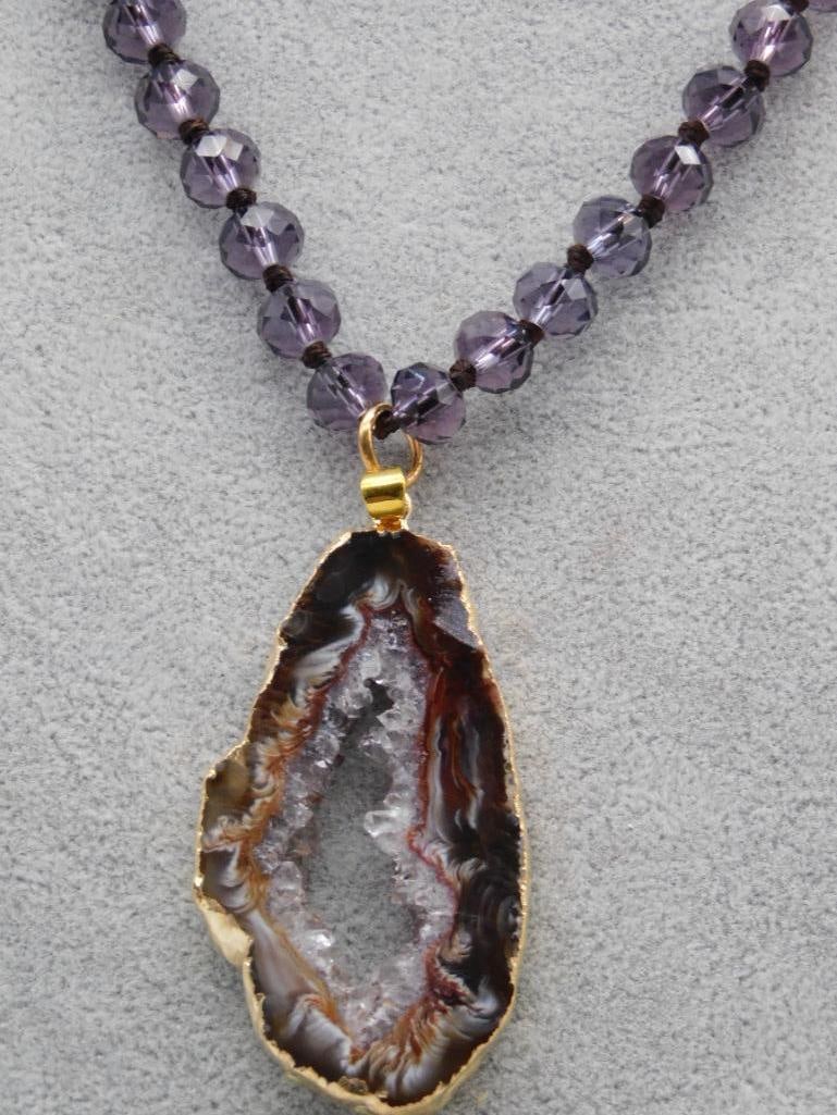 Purple Beaded Necklace With Geode Pendant ROCK STONE LAPIDARY SPECIMEN: Features a purple beaded necklace with clear and dark accents. | Central pendant is a natural geode with exposed crystals, framed in a gold-toned border. | Double-strand design for added elegance. | I