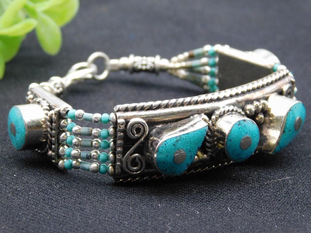 Vintage Bracelet with Turquoise Accents: Features a handcrafted design with multiple turquoise stone accents. | Made of silver with intricate beadwork and decorative etching. | Includes a lobster clasp closure for secure wear. | Measures app