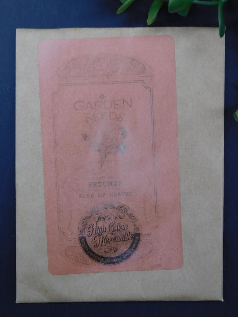 Vintage Petunia Garden Seeds Packet: Vintage garden seed packet labeled 'Petunia.'/n Features a decorative design and branding details./n The packet appears unopened and is in its original condition./n Marked 'High Colors Guaranteed.' /n