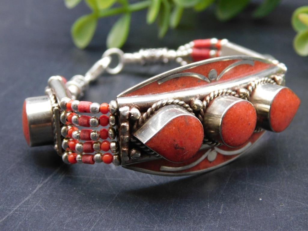 Silver Bracelet With Red Coral and Ornate Accent Beads: Features a silver-tone bracelet adorned with red coral stones. | Includes intricate metalwork and accent bead details. | Fitted with a secure lobster claw clasp for closure. | Measures approximately 7