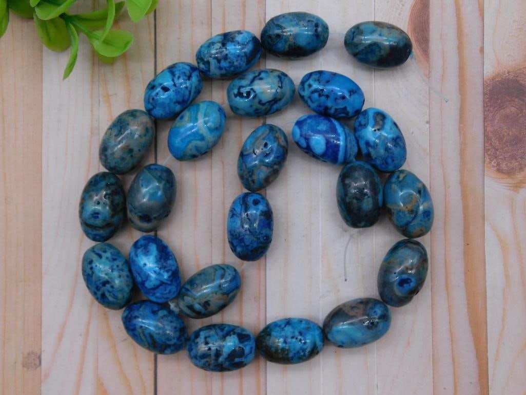 Strand of Blue Agate Oval Beads Rock Stone Lapidary Specimen: Strand of oval blue agate beads in varying shades of blue with natural patterns. | Approximately 27 beads included in the strand. | Beads are drilled and ready for stringing or jewelry-making. | Dimen