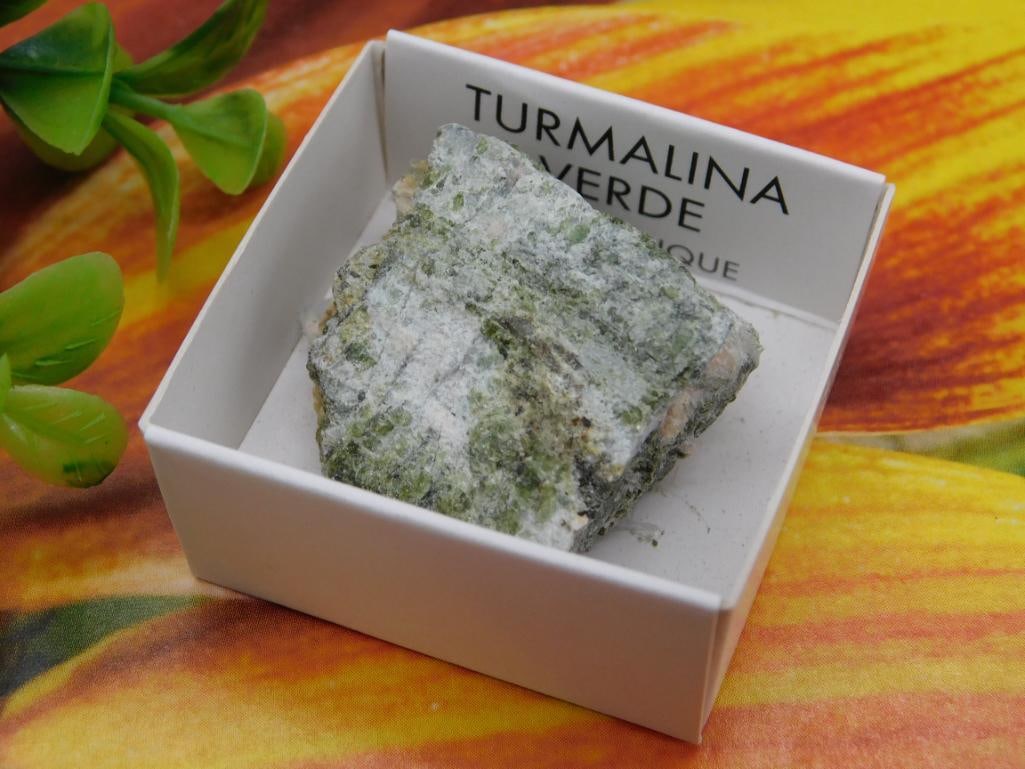 Green Tourmaline Mineral Specimen in Display Box Rock Stone Lapidary Specimen: - Green tourmaline mineral specimen labeled as 'Turmalina Verde' in a small display box. | - Specimen weighs approximately 29 grams according to the label. | - Comes in a square, white box for easy st
